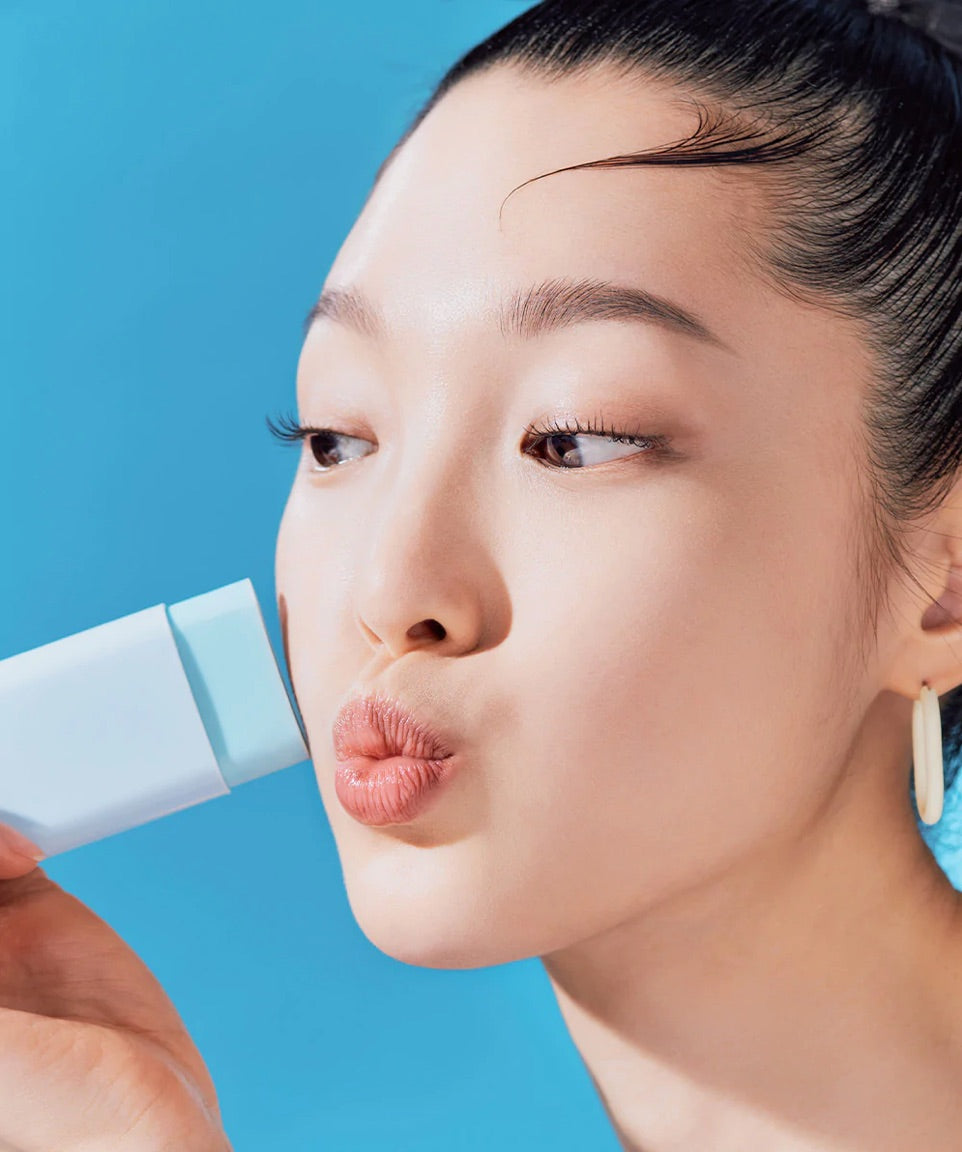 Woman holding a blue skincare product against a blue background