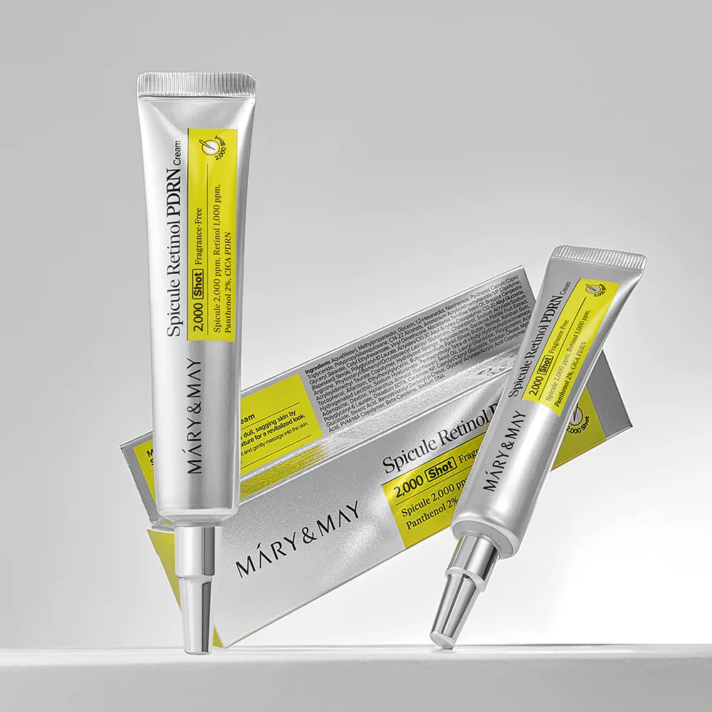 Two skincare serum tubes with a box on a gray background
