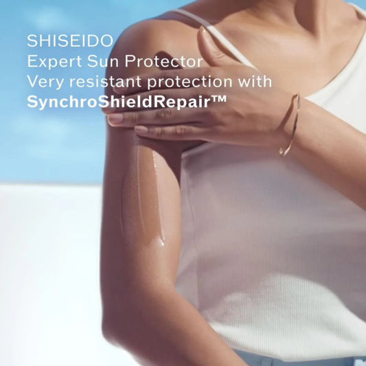Person wearing a white tank top with SHISEIDO sun protector product on a clear sky background