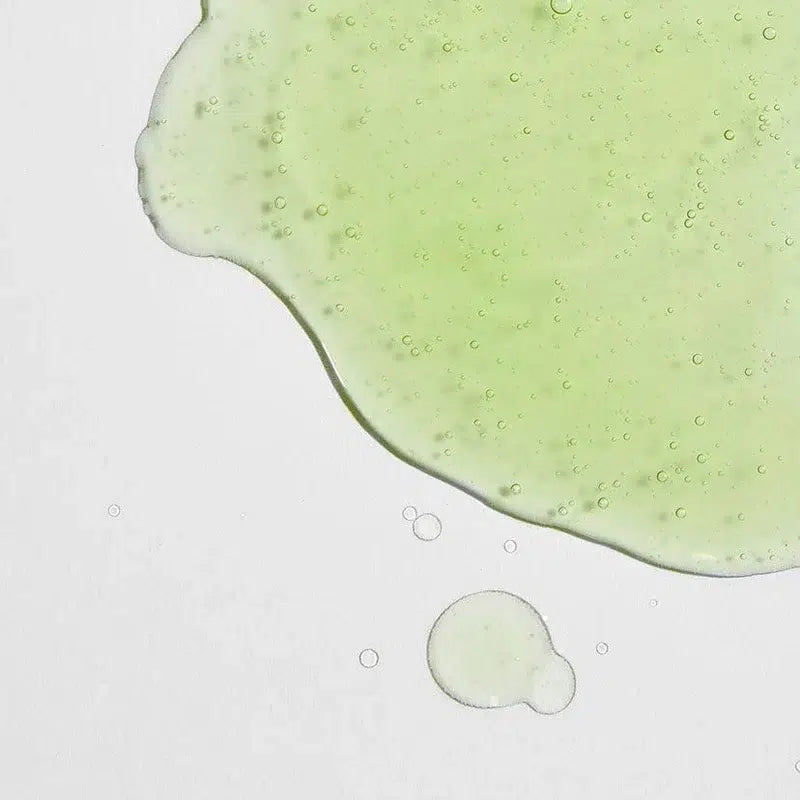 Close-up of a green liquid droplet on a white background