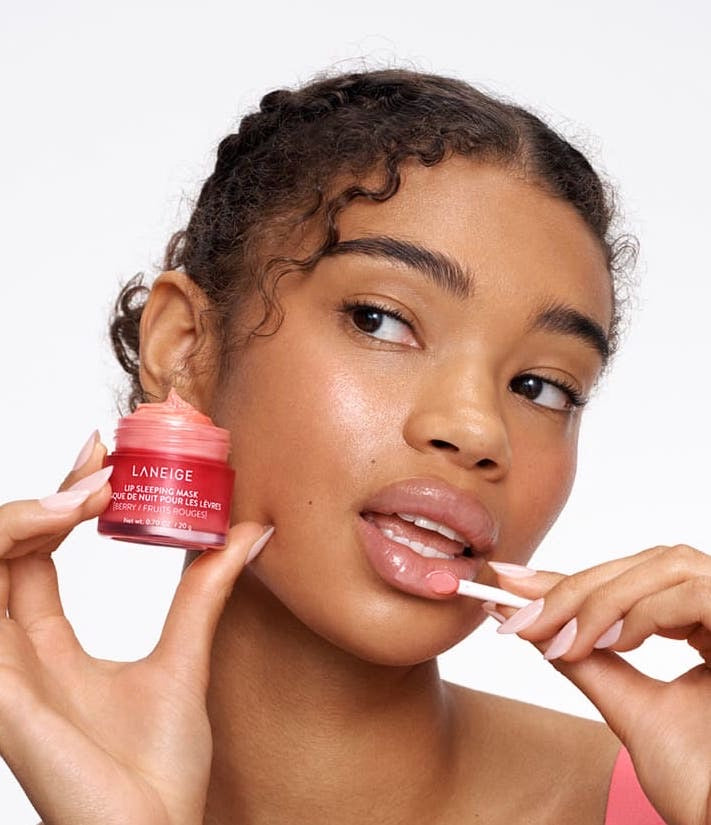 Woman applying lip balm from a Laneige container on a white background