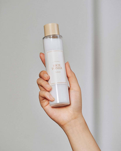Hand holding a bottle of face toner against a plain background