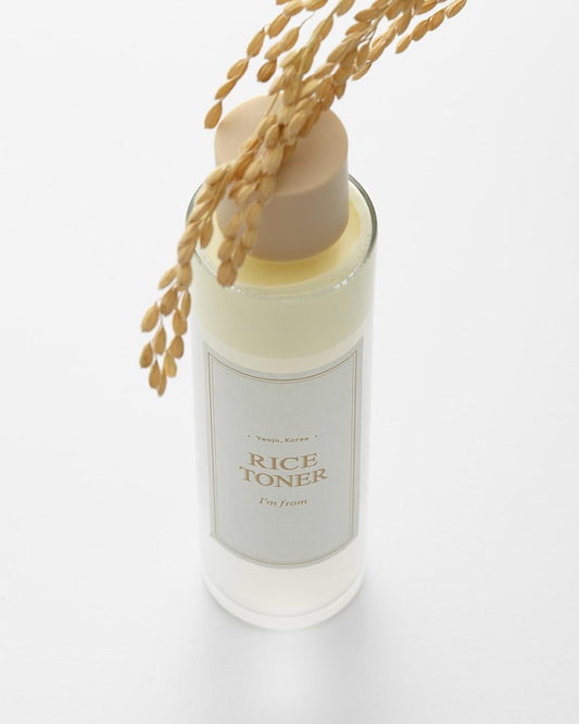 Bottle of rice toner with a beige cap on a white background