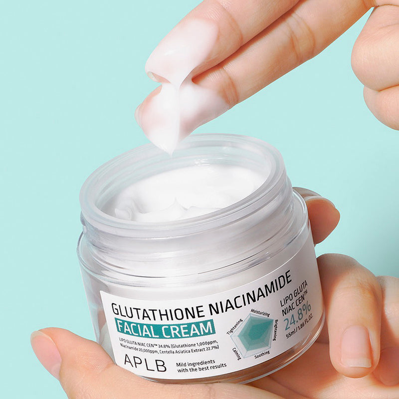 Hand applying facial cream from a jar labeled 'APLB' on a light blue background