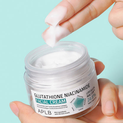 Hand applying facial cream from a jar labeled 'APLB' on a light blue background