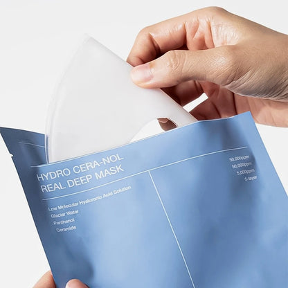Hand holding a Hydro Cera-Nol Real Deep Mask packaging against a white background