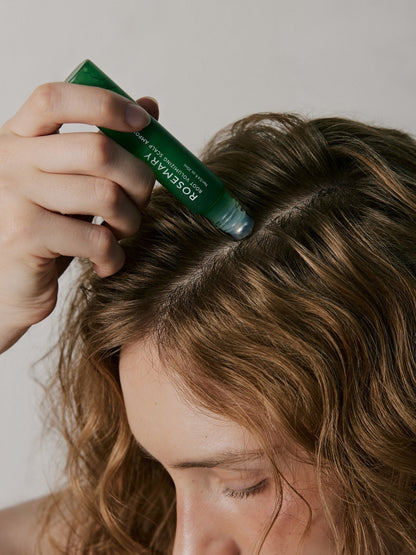 Person applying a green hair product to their hair with a brush.