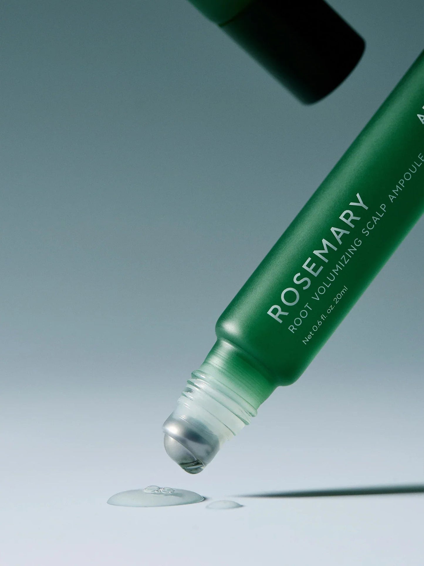 Green bottle of Rosemary root volumizing scalp ampoule with dropper on a light blue background