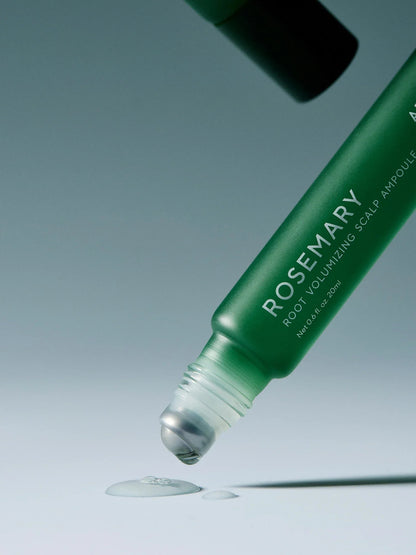 Green bottle of Rosemary root volumizing scalp ampoule with dropper on a light blue background