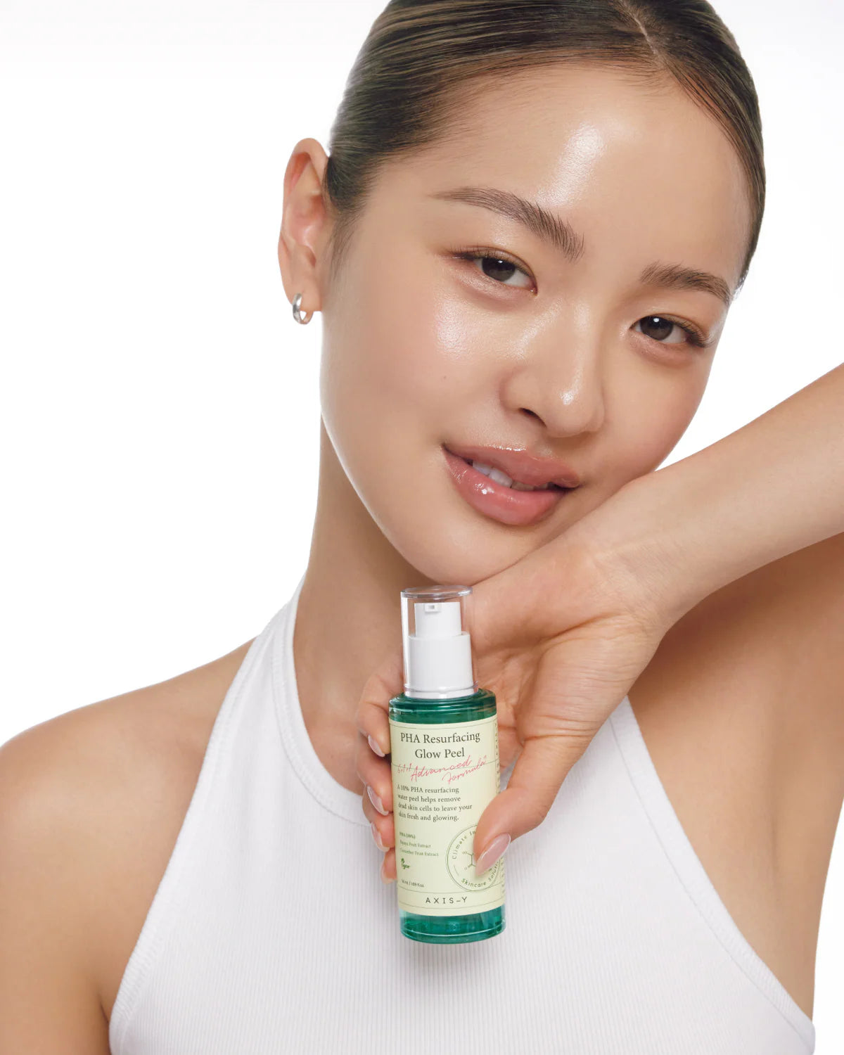 Woman holding a skincare bottle with a plain background