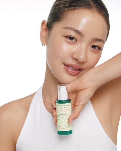 Woman holding a skincare bottle with a plain background