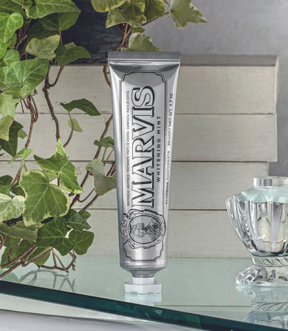 Marvis toothpaste tube on a glass surface with greenery in the background